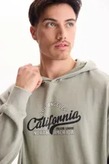 Buzo canguro con capucha verde militar, sin friza, con bolsillo delantero tipo kermesse y estampado frontal con la inscripción 'Los Angeles California College League North America'.