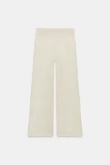 Pantalón de pierna ancha y tiro medio, confeccionado en tejido con textura arrugada. Presenta una cintura elástica destacada por un detalle de tejido en crochet a tono.