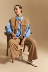 Camisa azul a rayas blancas, de manga larga con puños elastizados, entallada en la cintura y con cierre de botones frontales.