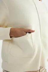 Abrigo de punto negro con cuello alto y cierre frontal completo. Presenta un diseño de corte recto con bolsillos frontales y terminaciones en tejido acanalado.