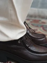 Zapato de cuero negro con cordones, detalle de pespuntes en la puntera y suela de goma con plataforma.