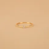 Anillo de oro 18k con diseño de alianza fina y un brillante engastado, presentado en conjunto con otros anillos de oro de diseño entrelazado.