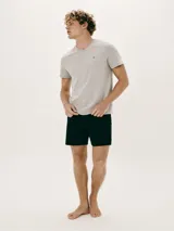 Pijama de hombre compuesto por una remera gris de cuello V con un pequeño bordado en el pecho y un short negro liso.