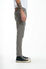 Pantalón cargo gris de gabardina, corte slim, con bolsillos laterales con solapa y bolsillos traseros con ojal y botón. Presenta efecto teñido en la tela.