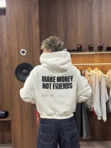 Hoodie de color blanco con capucha, corte holgado y estampado gráfico en la espalda con la frase 'MAKE MONEY NOT FRIENDS' en color negro.