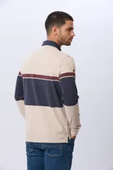 Remera polo de manga larga con diseño de bloques de color horizontales en tonos azul, verde y marrón. Presenta cuello clásico, cierre frontal con botones y bordado en el pecho. Cuenta con puños elásticos acanalados.