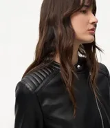Campera biker de poliuretano color verde oliva, con cierre frontal asimétrico, bolsillos laterales con cremallera y detalle capitoneado en los hombros.