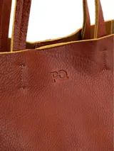 Cartera shopper de cuero color terracota, sin forro, con diseño amplio y asas de hombro.