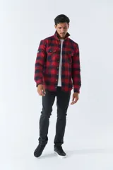 Sobrecamisa de algodón a cuadros color ladrillo, con interior de corderito, cierre con botones, bolsillos tipo cartera y logo en goma. El modelo usa talle M.