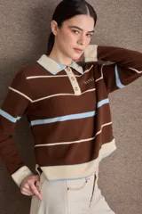 Buzo de punto con cuello polo y cierre frontal de tres botones. Diseño a rayas horizontales en tonos crema, bordó y mostaza, con detalle de bordado en el pecho.