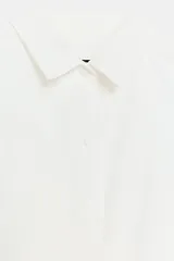 Top blanco de popelín sin mangas, con cuello camisero, corte cropped y cierre frontal con botones.