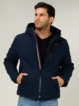 Campera soft shell Tommy Hilfiger color azul marino, con capucha, cierre frontal de cremallera con detalles tricolores y bolsillos con cierre en los laterales y en el pecho.