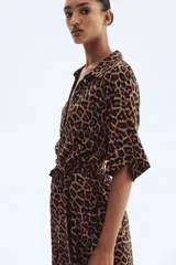 Vestido midi con estampado de leopardo, cuello camisero, manga corta y botonadura frontal. Presenta elástico en la cintura y cinturón extraíble para atar.