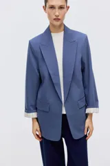 Blazer de sarga color azul, sin cierre, con solapas de pico, bolsillos delanteros con solapa y mangas largas.