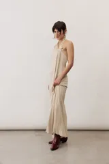 Vestido largo negro de corte al cuerpo con cuello halter y detalle de hebilla metálica dorada en el hombro con tira drapeada.