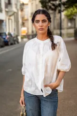 Blusa de algodón color blanco con bordado sutil en relieve, cuello redondo, cierre frontal con botones y mangas tres cuartos con terminación elástica.