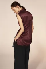 Vestido corto de cuello subido y sin mangas, confeccionado en tejido satinado. Presenta un detalle de fruncido lateral con abertura frontal y aplicación de encaje en el bajo.