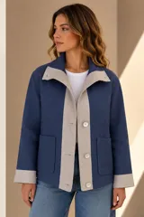 Campera de lino color azul con detalles en beige en la solapa, la tapeta de botones y los puños. Presenta botones de nácar y bolsillos frontales aplicados.