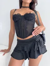 Corset negro de encaje y tul con estructura de varillas, escote corazón y tirantes finos. Presenta detalles de encaje en los bordes y paneles laterales transparentes.