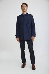 Gabardina de corte recto y estilo minimalista, color azul marino, con cuello camisero, cierre frontal oculto por solapa y puños ajustables con botón.