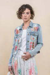 Campera de denim celeste con diseño artístico pintado a mano en tonos rosa, celeste y cobre, de corte clásico con bolsillos frontales y botones metálicos.