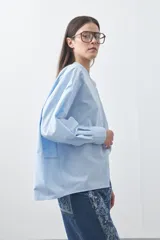 Camisa de manga larga en color celeste, con cuello mao y cierre frontal oculto. Presenta un diseño de silueta relajada con sisa caída y un bolsillo aplicado en el pecho.
