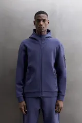 Campera canguro de Zara Athleticz, modelo relaxed fit, confeccionada en tejido técnico compacto elástico con mezcla de algodón en color azul marino. Cuenta con cuello subido con capucha, manga larga con bolsillo lateral con cierre, bolsillos frontales con cierre y acabado termofijado, cierre frontal de doble dirección y logo estampado en el bajo.