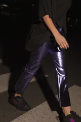 Pantalón de ecocuero color violeta metalizado, con corte capri semi oxford y tiro medio-alto. Presenta cierre frontal con botón metálico y bolsillos traseros.