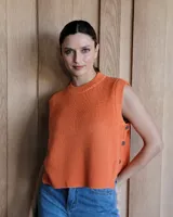Chaleco de tejido de punto color naranja quemado, sin mangas, con cuello redondo y botones decorativos en el lateral.