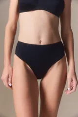 Bombacha tipo vedetina de tiro alto, confeccionada en tricot liso de color beige, con costuras reforzadas en los laterales.