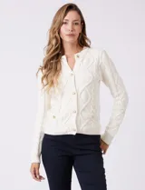 Cardigan blanco de punto aran con cuello redondo y cierre frontal de botones dorados. Presenta bolsillos simulados en la parte delantera.