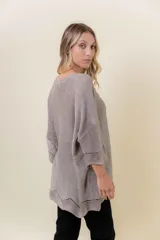 Buzo de tejido liviano con brillo sutil tipo lurex, color beige o dorado claro. Presenta un calce suelto (oversize) con mangas amplias y cuello redondo. El ruedo tiene un detalle de terminación festoneado con pequeños calados.