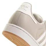 Championes Adidas modelo Superstar, color beige con las icónicas tres tiras laterales en blanco. Presenta la clásica puntera de goma, suela de plataforma blanca y base de goma color caramelo.