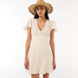 Vestido corto de corte evasé, con estampado floral sutil en tonos rosados y verdes sobre base blanca. Presenta escote en V y mangas cortas tipo mariposa.