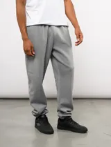 Pantalón de jogging de felpa con friza, color gris, con cintura elástica, bolsillos laterales y puños en los tobillos. Presenta un parche con el logo de Umbro en la parte superior delantera.