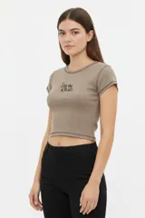 Remera crop negra de manga corta, con costuras visibles en contraste, cuello redondo y un estampado en el pecho con diseño de candado en forma de corazón.