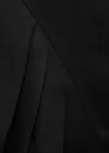 Vestido corto de corte evasé en color negro, con cuello barco y tirantes anchos. Presenta un diseño sin mangas con detalle de pliegues en la falda y cierre de cremallera en la parte posterior.