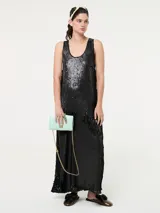 Vestido largo sin mangas, confeccionado completamente en lentejuelas negras, con escote redondo y tajos laterales en la falda.