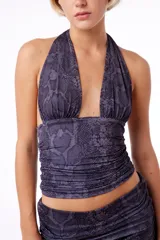 Top negro con estampado de piel de serpiente, drapeado en los laterales, con tiras largas para anudar en la espalda y logo metálico en el centro del pecho.