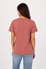 Remera de manga corta color beige, con cuello redondo y diseño al cuerpo. Presenta un estampado frontal multicolor de estilo veraniego con temática marina y detalles con glitter.