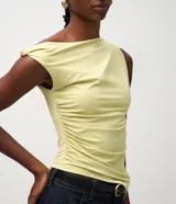 Blusa de microfibra color amarillo claro, sin mangas, con escote de hombro único, detalle torcido en el hombro y fruncidos en todo el diseño. Presenta un corte ajustado y bajo asimétrico.