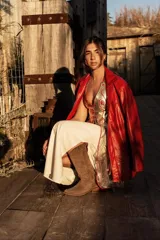 Top de cuero dorado brillante con tela bordada con canutillos dorados que cae a los costados y detalles en cuero rojo. Se ajusta en cuello y espalda.