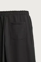 Pantalón jogger de corte relajado y pernera ancha, confeccionado en tejido de algodón con interior perchado. Cuenta con cintura elástica ajustable mediante cordón interior, bolsillos laterales y un bolsillo trasero de plastrón.