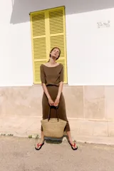 Bolso tipo shopper confeccionado en yute trenzado, con doble asa de mano en cuero sintético color marrón.