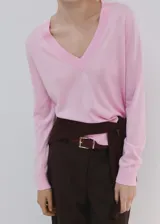 Chaleco de punto fino color rosado, con diseño recto, cuello en V y mangas largas.