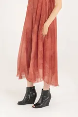 Vestido midi lencero de viscosa y seda, color salmón, con breteles regulables, escote en V, silueta evasé con vuelo, bolsillos laterales y ruedo deshilachado.
