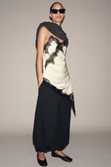 Pantalón de tiro medio, color negro con rayas diplomáticas finas blancas. Cintura elástica ajustable con cordones y bajo abullonado con elástico.
