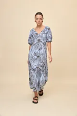 Vestido largo celeste con estampado botánico en tonos marrones, escote en V, mangas cortas abullonadas y falda con volado en el bajo.