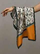 Pañuelo cuadrado de satén con estampado floral en tonos blancos, verdes y amarillos, con una franja ancha de color mostaza en uno de los extremos y bordes en verde oscuro.