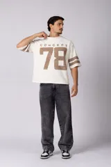 Remerón de corte oversize con cuello redondo y mangas cortas. Presenta un diseño estampado frontal con la palabra 'CONCEPT' y el número '78' en efecto desgastado, además de dos franjas horizontales en las mangas.